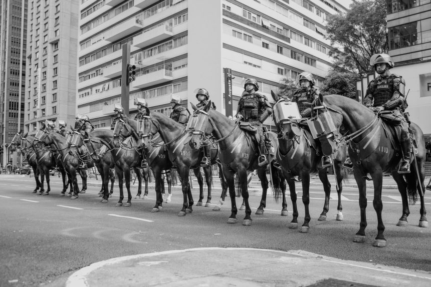Policiais montados patrulham uma rua de São Paulo em imagem em preto e branco.