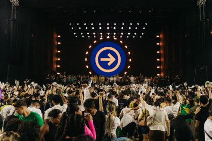 Público acompanha uma apresentação musical em palco iluminado durante um festival no Brasil.