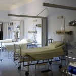 Enfermaria hospitalar ampla, com vários leitos vazios e equipamentos médicos.