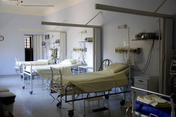 Enfermaria hospitalar ampla, com vários leitos vazios e equipamentos médicos.