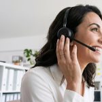 Mulher usando headset em um ambiente de atendimento e comunicação com o público.